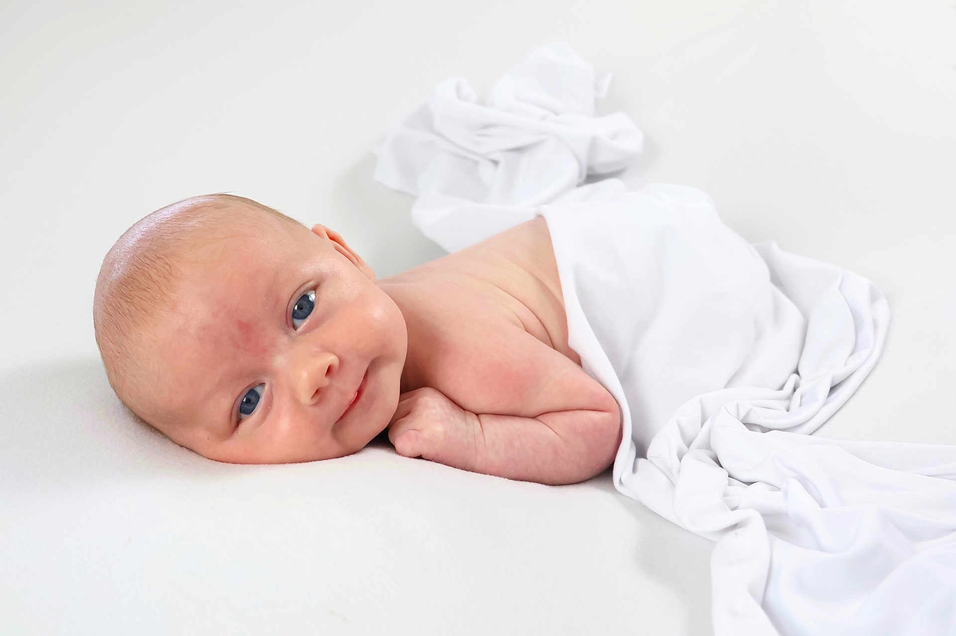 Giorgio joined the competition — help win amazing prizes! baby, infant, newborn, blue_eyes, white_cloth, soft_surface, lying_down, curious, smiling, skin, head, face, arm, minimalistic, blanket, cute, child, portrait, indoors, resting