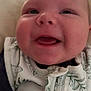 Oakley is registered to the contest to win money with this photo: baby, smiling, close_up, infant, face, chubby_cheeks, clothing, white_outfit, green_pattern, zipper, happy, cute, young_child, portrait, indoors, soft_light, skin, hand, person, expression