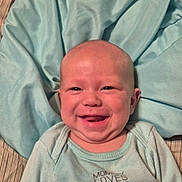 Raylin is registered to the contest to win money with this photo: baby, infant, child, smiling, happy, portrait, face, lying_down, blanket, bedding, aqua, clothing, onesie, indoor, close_up, head, eyes, mouth, cheeks, cozy