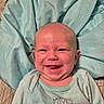 baby, infant, child, smiling, happy, portrait, face, lying_down, blanket, bedding, aqua, clothing, onesie, indoor, close_up, head, eyes, mouth, cheeks, cozy