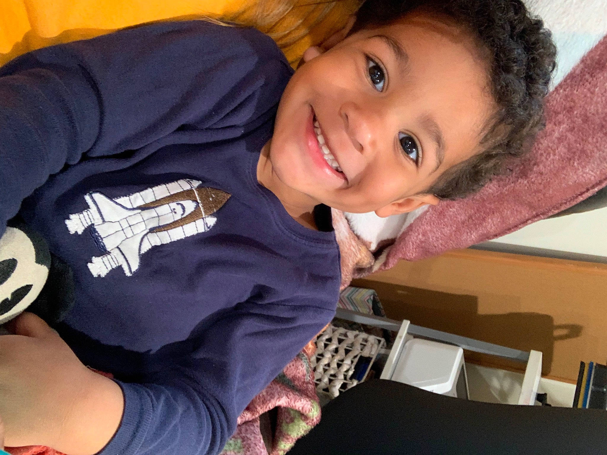 Boston is registered to the contest to win money with this photo: cheek, elbow, finger, fun, hand, happy, human_body, iris, joy, mouth, neck, nose, organ, person, shipping_box, sitting, sleeve, smile, t_shirt, thigh