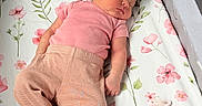Riley is registered to the contest to win money with this photo: newborn, baby, sleeping, infant, portrait, floral, bassinet, crib, pink_clothing, pants, socks, pacifier, face, closed_eyes, indoor, nursery, blanket, patterned_bedding, resting, peaceful