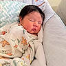 newborn, baby, sleeping, infant, portrait, hospital, bedding, blanket, floral_pattern, onesie, swaddled, peaceful, face, closed_eyes, dark_hair, indoors, bed, pillow, cozy, resting