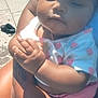 Ronoyah is registered to the contest to win money with this photo: baby, child, infant, person, holding, arm, tattoo, outdoor, sunlight, clothing, shorts, shirt, hand, footwear, shoe, tiles, skin, cute, peaceful, portrait