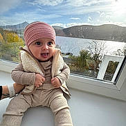 Oliwia joined the competition — help win amazing prizes! baby, child, window, lake, mountains, cloudy_sky, headband, vest, beige_clothing, tongue_out, blue_eyes, raindrops, nature, outdoor_view, smiling, sitting, cozy, hand, , , person