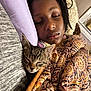 animal, blanket, child, closeup, cozy, cute, face, indoor, kitten, nap, patterned_blanket, peaceful, pillow, portrait, rest, sleeping, soft_lighting, tabby_cat, warm, young_child