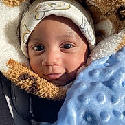 Zymir is registered to the contest to win money with this photo: baby, child, face, hat, blanket, blue_blanket, jacket, fur_jacket, cozy, cute, infant, portrait, close_up, warm, sunlight, expression, smile, clothing, indoors, person