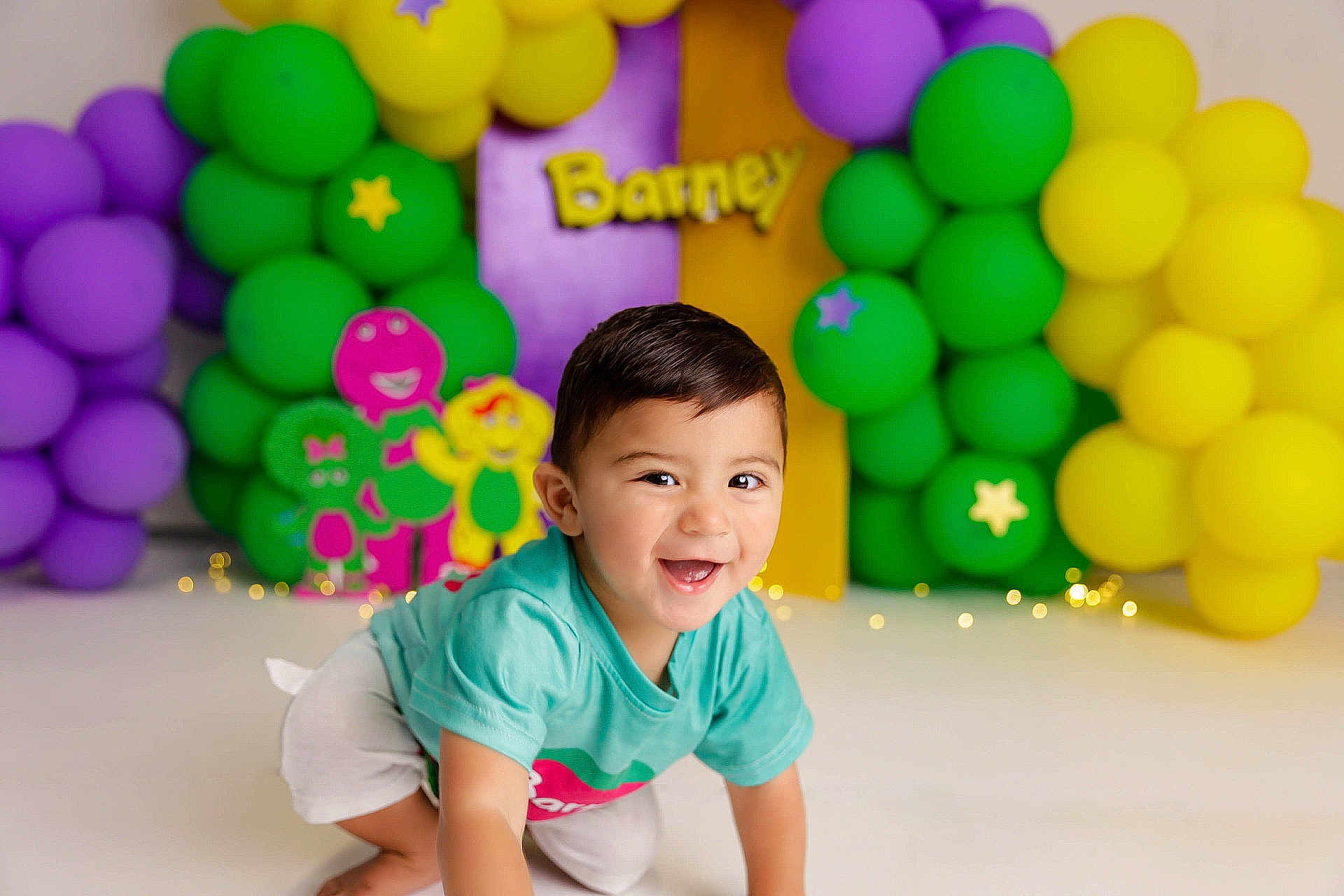 Mikel joined the competition — help win amazing prizes! toddler, child, smiling, crawling, balloons, purple_balloons, green_balloons, yellow_balloons, barney, background, decorations, playful, happy, indoor, cute, short_hair, casual_clothing, colorful, party, celebration