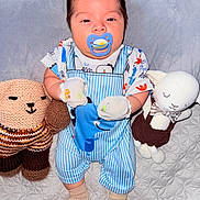 Asher joined the competition — help win amazing prizes! baby, infant, child, pacifier, plush_toys, stuffed_animals, sitting, indoors, portrait, blue_overalls, striped_clothing, onesie, socks, blanket, bed, bedding, cuddling, wide_eyed, nursery, photography