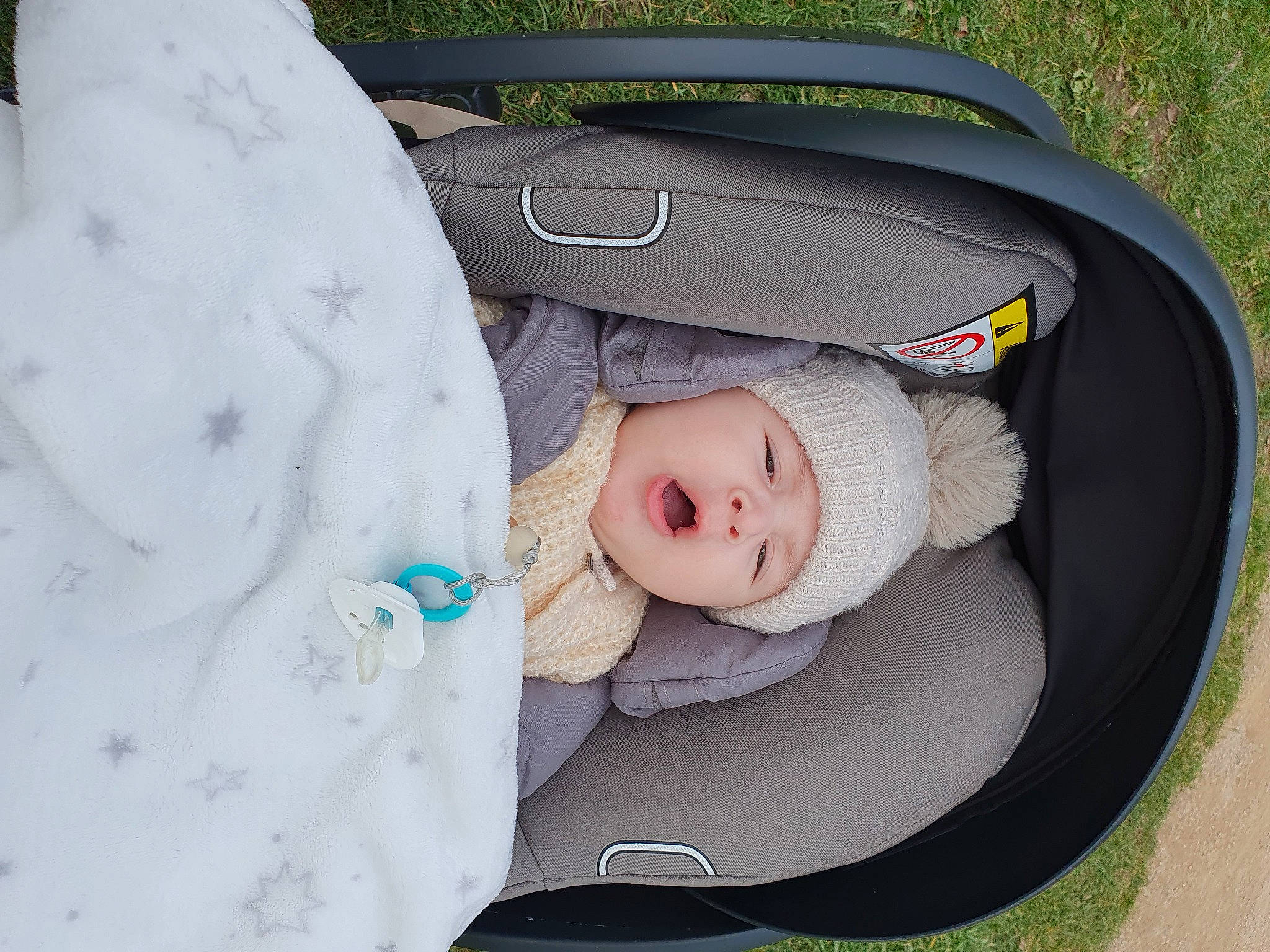 Eyden participe au concours pour gagner de l'argent avec cette photo : auto_part, baby, baby_carriage, baby_products, baby_toddler_clothing, bag, baggage, car_seat, child, comfort, family_car, fashion_accessory, grass, headwear, infant_bed, linens, luggage_and_bags, pattern, person, sitting