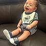 Carlos joined the competition — help win amazing prizes! baby, child, laughing, smiling, sitting, couch, leather, shoes, striped_clothing, bib, happy, infant, cute, indoor, young, person, footwear, relaxed, expression, small