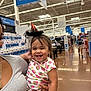 toddler, child, adult, store, shopping_aisle, smiling, hat, witch_hat, clothing, holding, person, indoor, shopping, retail, happy, cute, casual, bracelet, hair, portrait
