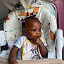 Elidja participe au concours pour gagner de l'argent avec cette photo : bib, blanket, child, clothing, earrings, expression, face, food, hair_braids, hand, high_chair, indoor, mickey_mouse, person, pigtails, portrait, seat, smudge, toddler, toy