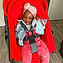 Elidja a rejoint le concours — aidez-le/la à gagner de superbes lots ! baby, baby_clothes, child, childhood, clothing, denim_jacket, flooring, footwear, furniture, happy, indoor, jacket, person, pink_turban, red_stroller, room, seated, smile, toy, wooden_floor