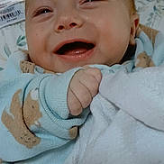 James is registered to the contest to win money with this photo: baby, smiling, infant, blanket, blue_clothing, teddy_bear_pattern, happy, cute, close_up, child, soft_texture, portrait, indoors, cozy, face, small_hand, sleepwear, newborn, warm, joyful