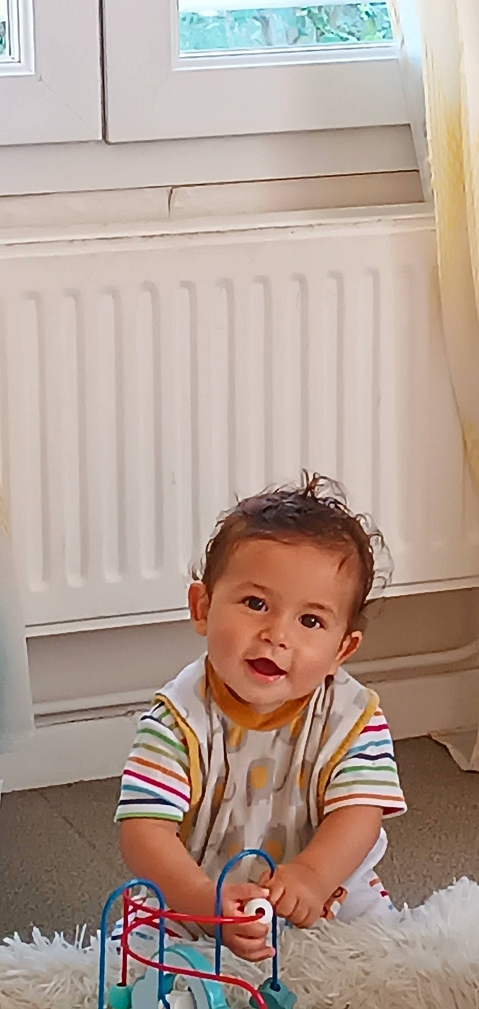 Kaiis participe au concours pour gagner de l'argent avec cette photo : baby, baby_toddler_clothing, cheek, child, curtain, flooring, fun, happy, pattern, person, plant, portrait_photography, room, sitting, sleeve, smile, t_shirt, toddler, tree, wood