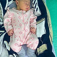 Saona participe au concours pour gagner de l'argent avec cette photo : baby, sleeping, blanket, pink_clothing, floral_pattern, socks, towel, infant, cozy, cute, resting, child, young, soft_texture, indoors, portrait, hands, feet, peaceful, nursery