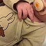 baby, pacifier, onesie, hand, infant, clothing, beige, cute, toddler, sleepwear, child, soft, fabric, closeup, face, skin, bed, comfort, nursery, animal_print