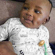 Makan participe au concours pour gagner de l'argent avec cette photo : baby, child, smiling, onesie, lion_print, pacifier, hand, couch, indoor, face, person, clothing, comfort, cute, infant, young_child, portrait, resting, happy, closeup