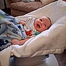 Brendan is registered to the contest to win money with this photo: baby, blanket, blanket_pattern, blue, couch, cozy, cushion, face, furniture, happy, home, indoors, infant, laying, person, portrait, seat, smile, toddler, white