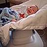 baby, baby_rocker, blanket, child, clothing, comfort, cozy, cushion, cute, face, furniture, happy, home, indoor, infant, lying_down, person, relaxation, smile, wrapped