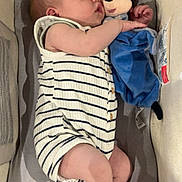 Elyo participe au concours pour gagner de l'argent avec cette photo : arm, baby, bassinet, child, comfort, cute, face, foot, hand, indoors, infant, mickey_mouse, nap, peaceful, plush_toy, resting, sleeping, soft_toy, striped_clothing, toy