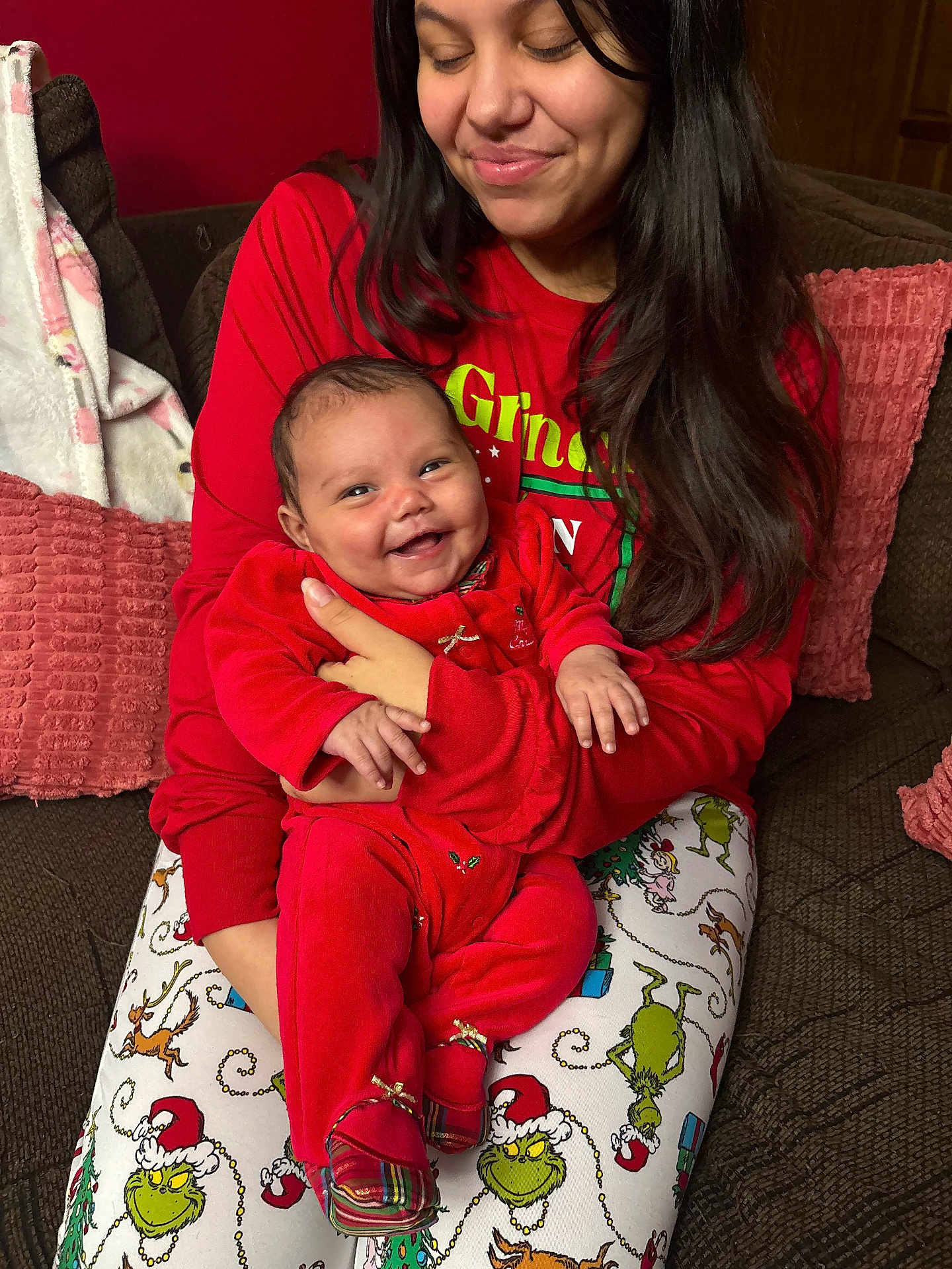 Jolene is registered to the contest to win money with this photo: baby, celebration, christmas_theme, couch, cozy, family, festive, happy, holding, holiday_pajamas, home, indoor, infant, long_hair, person, pillow, plaid_shoes, red_clothing, smile, woman