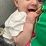 baby, infant, smiling, happy, cuddling, blanket, green_shirt, person, hand, face, closeup, soft, cozy, indoor, comfort, expression, cute, skin, clothing, resting