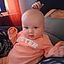 Journey joined the competition — help win amazing prizes! baby, child, onesie, peach_color, sitting, indoor, person, face, cheeks, hand, lap, clothing, curtain, red_curtain, furniture, adult, casual, relaxed, portrait, warm_lighting