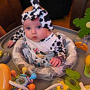 Journey joined the competition — help win amazing prizes! baby, infant, child, cow_print, headband, baby_activity_center, toys, colorful, curious, indoor, couch, seat, clothing, person, face, hands, wooden_floor, playtime, cute, expression