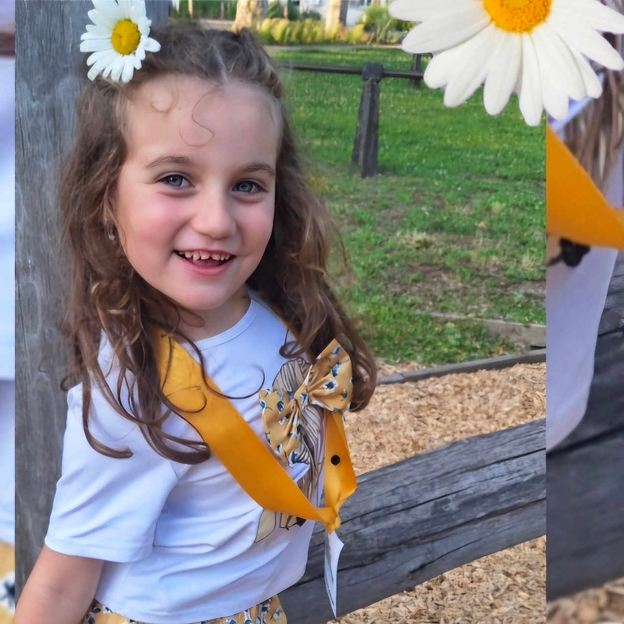 Louane participe au concours pour gagner de l'argent avec cette photo : bow, casual_clothing, child, cute, daisy, flower, girl, grass, happy, nature, outdoor, park, playground, portrait, smiling, sunlight, wood_chips, wood_post, yellow_clothing, young