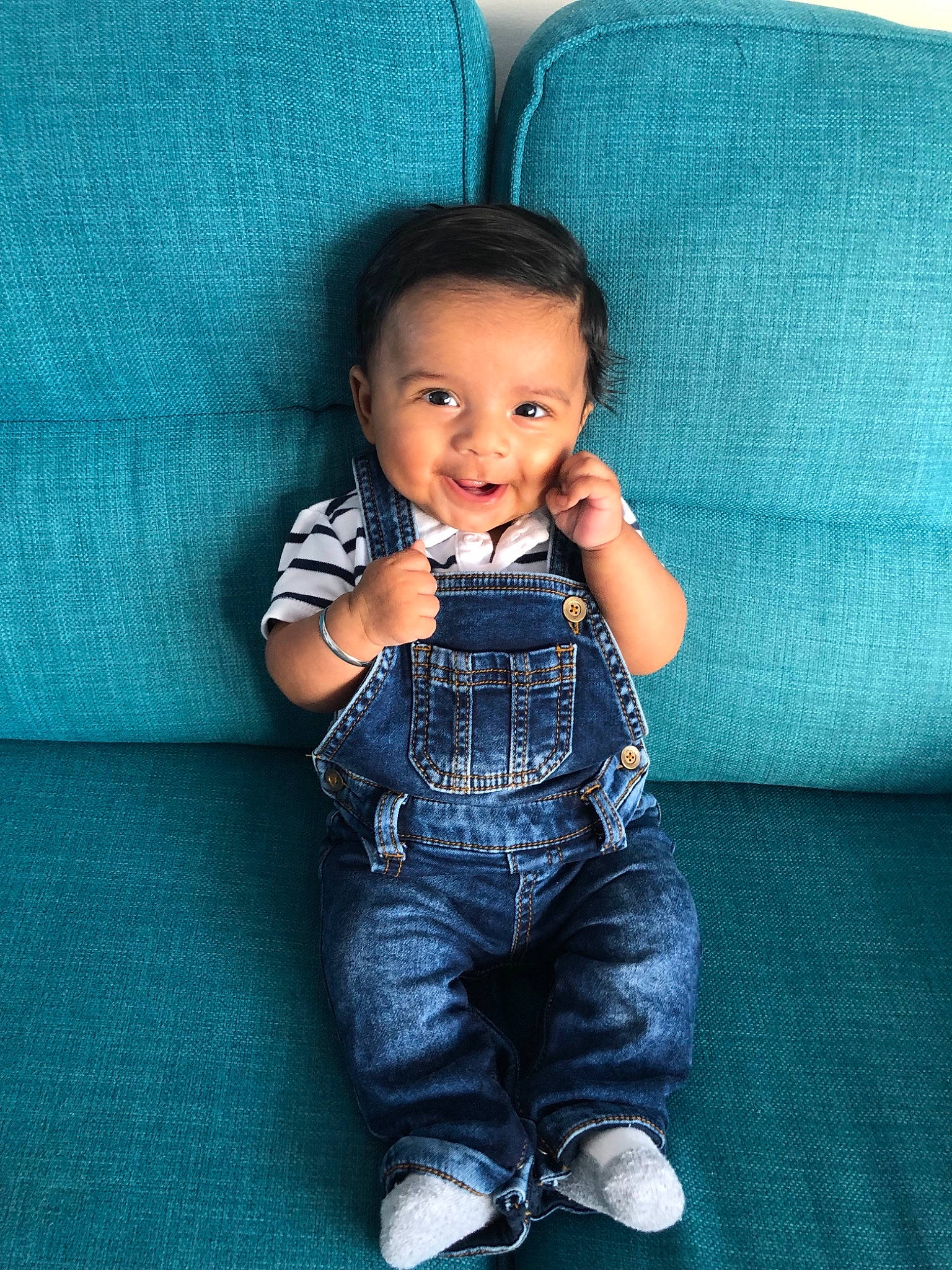 Amar is registered to the contest to win money with this photo: baby, black_hair, blue, cheek, child, cool, denim, head, jeans, overall, person, sitting, skin, smile, standing, textile, toddler