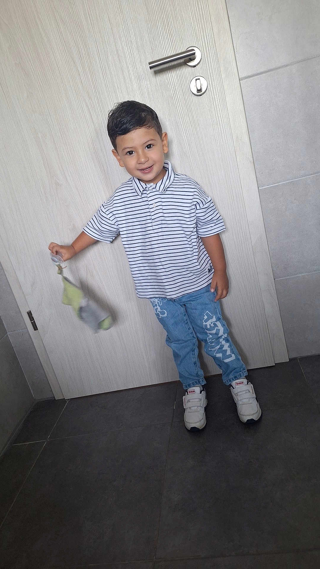 Liham a rejoint le concours — aidez-le/la à gagner de superbes lots ! child, boy, smile, striped_shirt, blue_jeans, sneakers, indoor, door, floor_tiles, holding_object, casual_clothing, happy, portrait, standing, short_hair, young, person, clothing, footwear, light_background