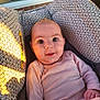 baby, infant, car_seat, patterned_fabric, face, smiling, pink_clothing, cozy, indoors, window, natural_light, child, cute, portrait, young_child, seat, head, happy, skin, hand