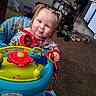 toddler, child, baby, smiling, sitting, activity_walker, toy, playtime, indoor, home, carpet, chair, colorful, blonde_hair, portrait, face, eyes, clothing, furniture, family_photo