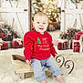 baby, barefoot, child, christmas, cozy, decorations, festive, fur_rug, happy, holiday, indoor, jeans, portrait, presents, red_sweater, sitting, sled, smiling, wooden, wreath