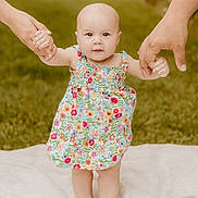Oaklie is registered to the contest to win money with this photo: baby, child, flowered_dress, holding_hands, outdoor, grass, blanket, walking, support, toddler, cute, person, skin, barefoot, summer, family, helping_hands, nature, portrait, happy
