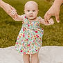 baby, child, flowered_dress, holding_hands, outdoor, grass, blanket, walking, support, toddler, cute, person, skin, barefoot, summer, family, helping_hands, nature, portrait, happy