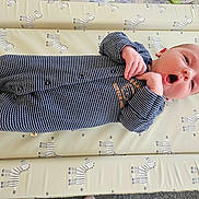 Felix is registered to the contest to win money with this photo: baby, infant, onesie, striped_clothing, lying_down, zebra_pattern, mattress, cute, small_hands, expression, face, head, newborn, child, soft_lighting, indoor, sleepwear, resting, patterned_bedding, adorable