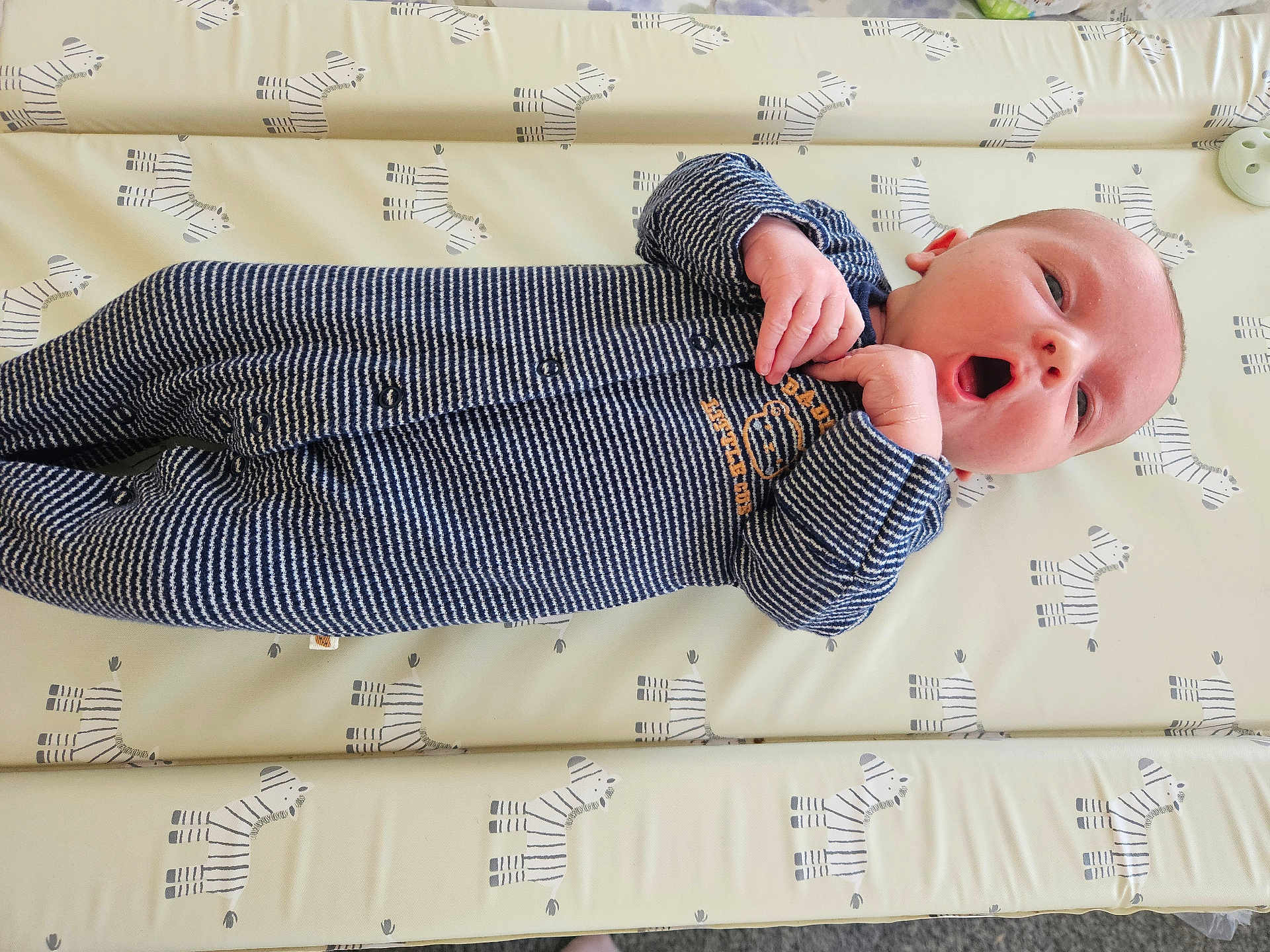 Felix is registered to the contest to win money with this photo: baby, infant, onesie, striped_clothing, lying_down, zebra_pattern, mattress, cute, small_hands, expression, face, head, newborn, child, soft_lighting, indoor, sleepwear, resting, patterned_bedding, adorable