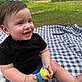 baby, child, smiling, toy, plush_toy, blanket, outdoor, grass, house, fence, black_shirt, blue_shorts, happy, sitting, cute, person, summer, daylight, nature, playtime