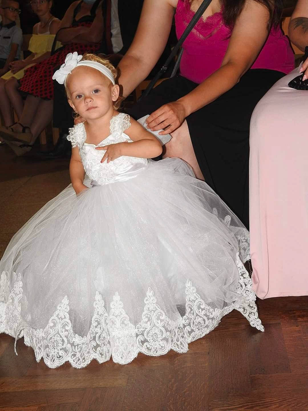 Naomye a rejoint le concours — aidez-le/la à gagner de superbes lots ! bridal_accessory, bridal_clothing, bridal_party_dress, dress, embellishment, event, fashion_design, flash_photography, flooring, formal_wear, gown, hairstyle, happy, headgear, headpiece, person, petal, pink, ruffle, toddler