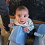baby, child, toy, scooter, blue, indoor, floor, chalkboard, chalk, hand, person, legs, curious, playful, expression, clothing, wooden_floor, wheels, furniture, young