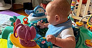 Howard joined the competition — help win amazing prizes! activity_center, baby, baby_gear, baby_toys, bib, child, colorful, face, happy, head, household, indoor, infant, onesie, play_mat, playroom, portrait, side_profile, sitting, toy_elephant