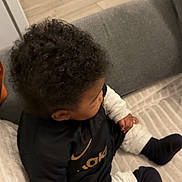 Kaydenn participe au concours pour gagner de l'argent avec cette photo : baby, blanket, child, couch, cozy, curly_hair, flooring, hand, home, indoor, logo, nike, portrait, shirt, side_profile, sitting, socks, sofa, toddler, wooden_floor