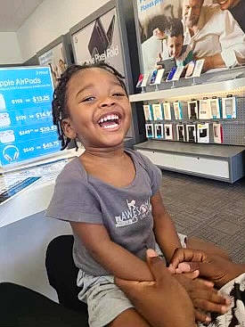 Lamar is registered to the contest to win money with this photo: child, event, fun, gesture, happy, human_leg, joint, joy, knee, lap, leisure, organ, person, room, shorts, sitting, skin, smile, snapshot, t_shirt