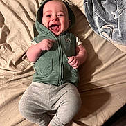 Casper joined the competition — help win amazing prizes! baby, child, infant, smiling, laughing, portrait, lying_down, bed, blanket, hooded_clothing, green_outfit, gray_pants, bare_feet, hands, face, indoor, bedroom, cozy, happy, photography