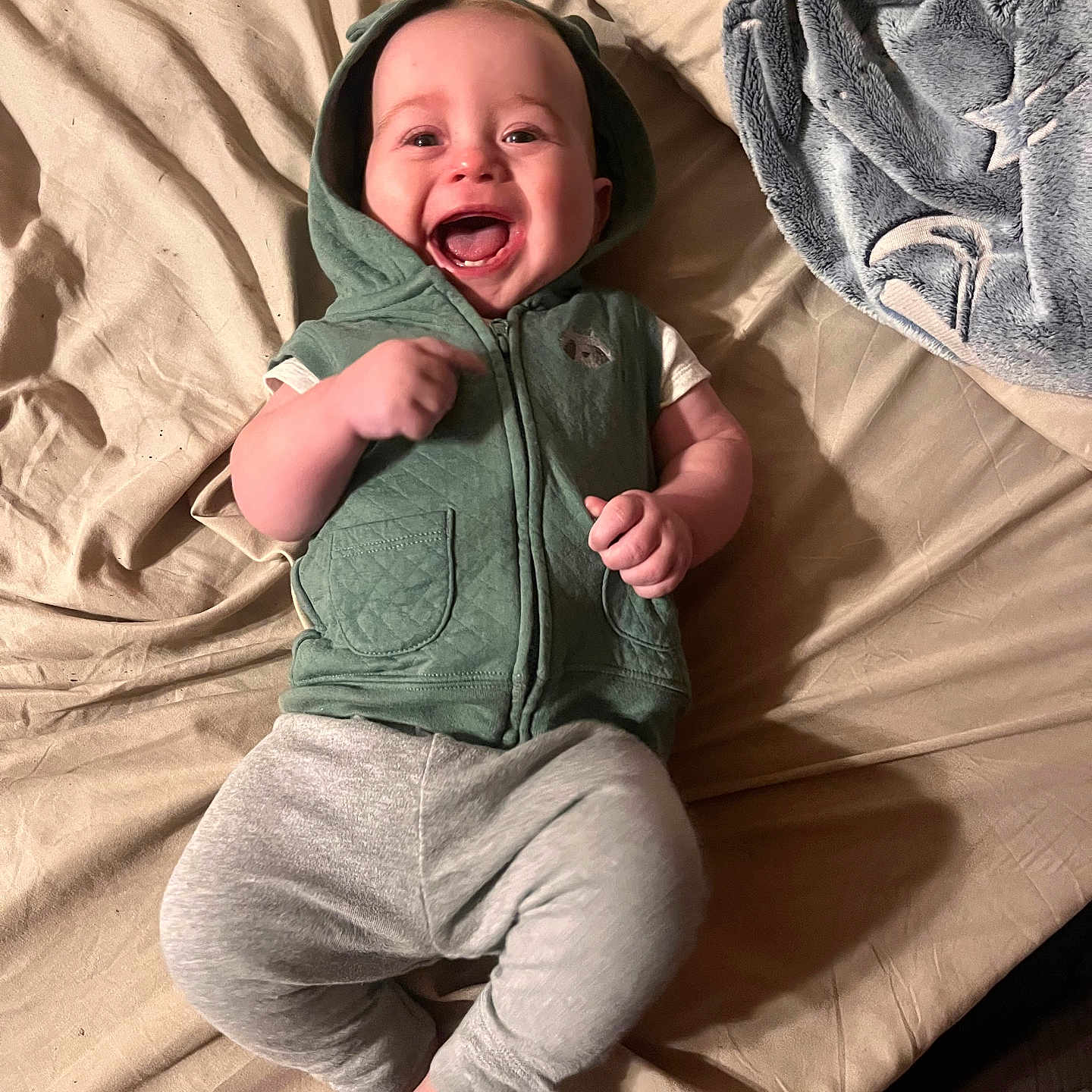 Casper joined the competition — help win amazing prizes! baby, child, infant, smiling, laughing, portrait, lying_down, bed, blanket, hooded_clothing, green_outfit, gray_pants, bare_feet, hands, face, indoor, bedroom, cozy, happy, photography