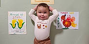 Marcus May Jr is registered to the contest to win money with this photo: barefoot, child, clothing, colorful, corn, cute, drawing, floor, foam_mat, home, indoor, long_sleeve, pants, pose, smiling, standing, thanksgiving, toddler, turkey, wall_art