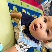 Marcus May Jr joined the competition — help win amazing prizes! baby, child, infant, face, eyes, mouth, arm, clothing, bib, pattern, animal_print, play_mat, colorful, indoor, floor, carpet, cute, curious, person, young